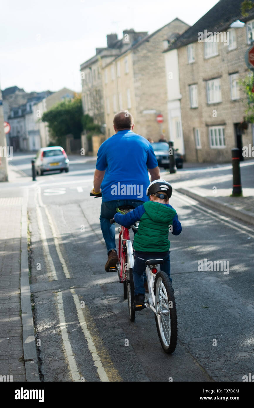 A father and son cycling together on a tandem style bicycle and trailer, Cirencester