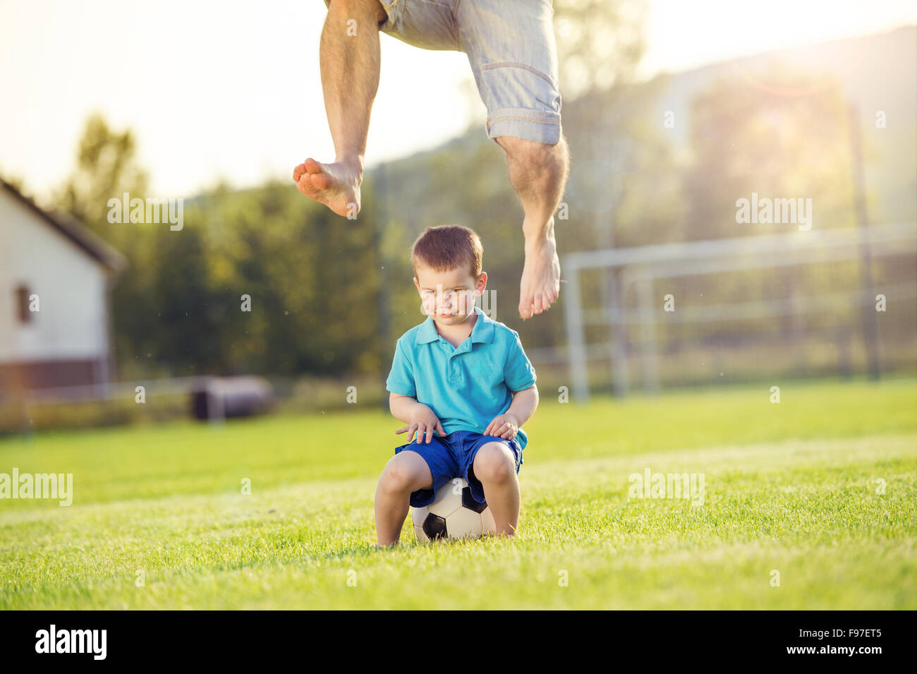 Young father with his little son playing football on football pitch Stock Photo