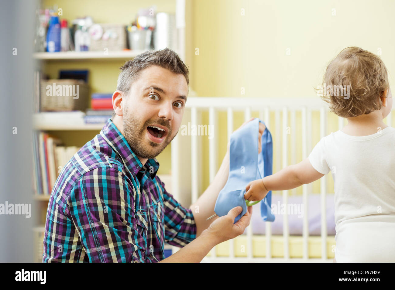 Young father with his damaged tie and his little daughter with scissors Stock Photo