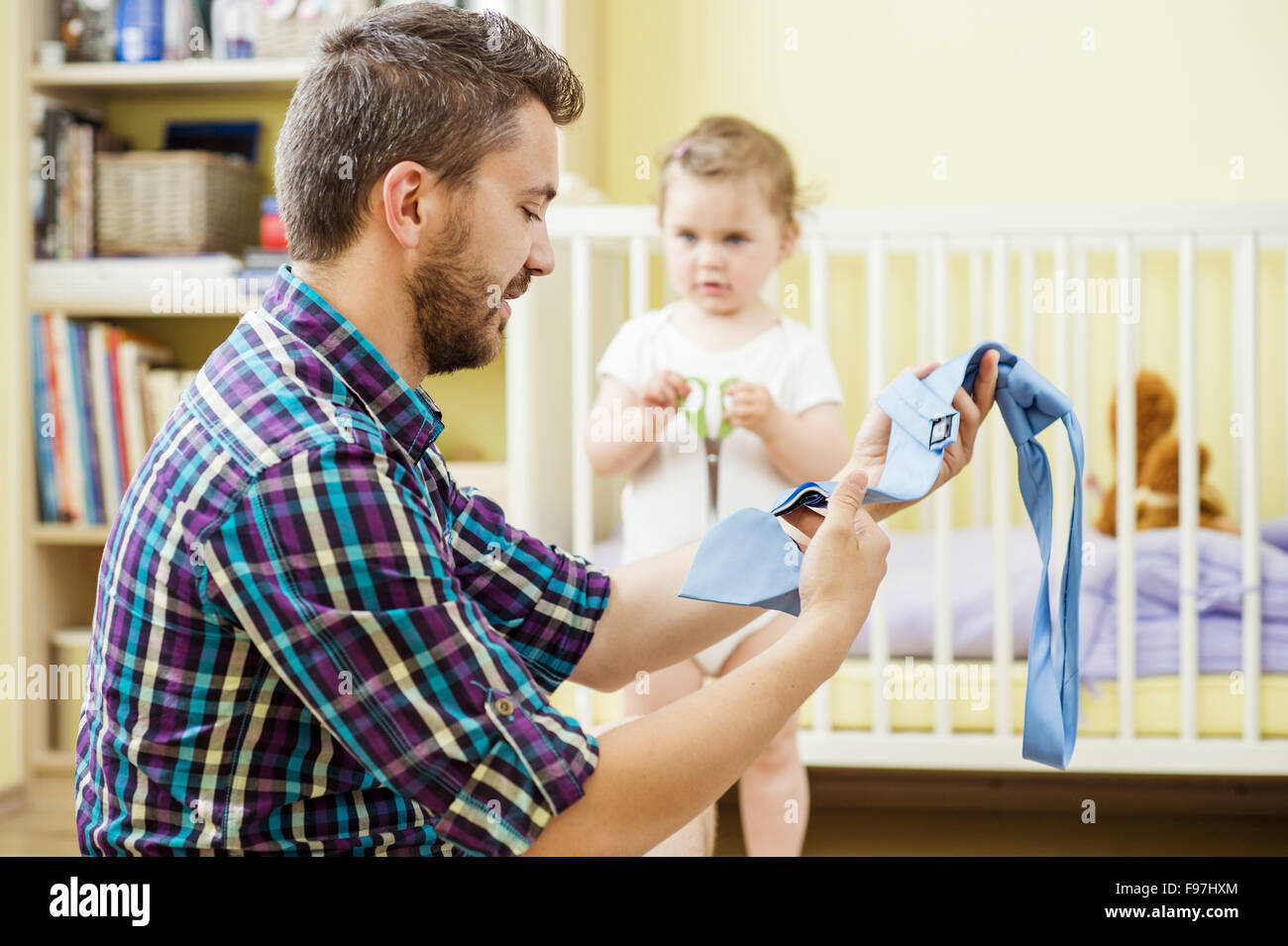 Young father with his damaged tie and his little daughter with scissors Stock Photo