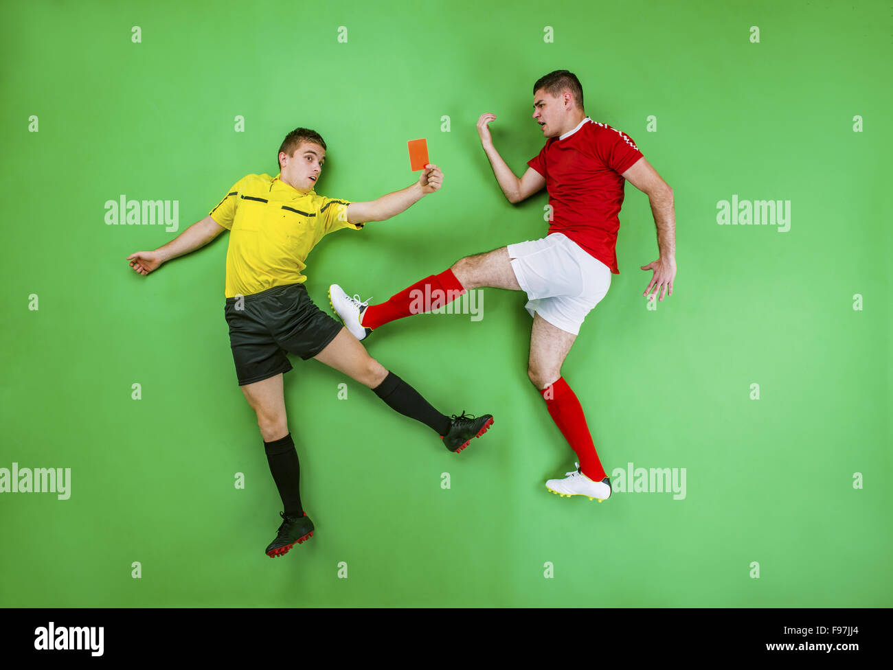 Referee giving red card to a football player. Studio shot on a green background. Stock Photo