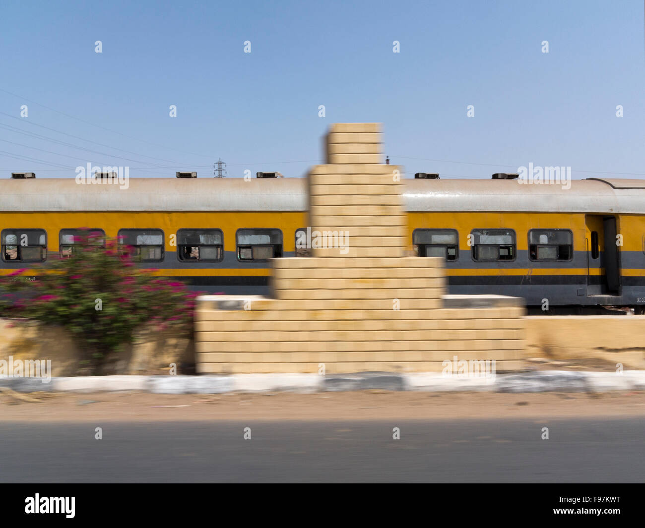 Train carriages passing at speed with movement blur on road and lamp post, Egypt, Africa Stock Photo