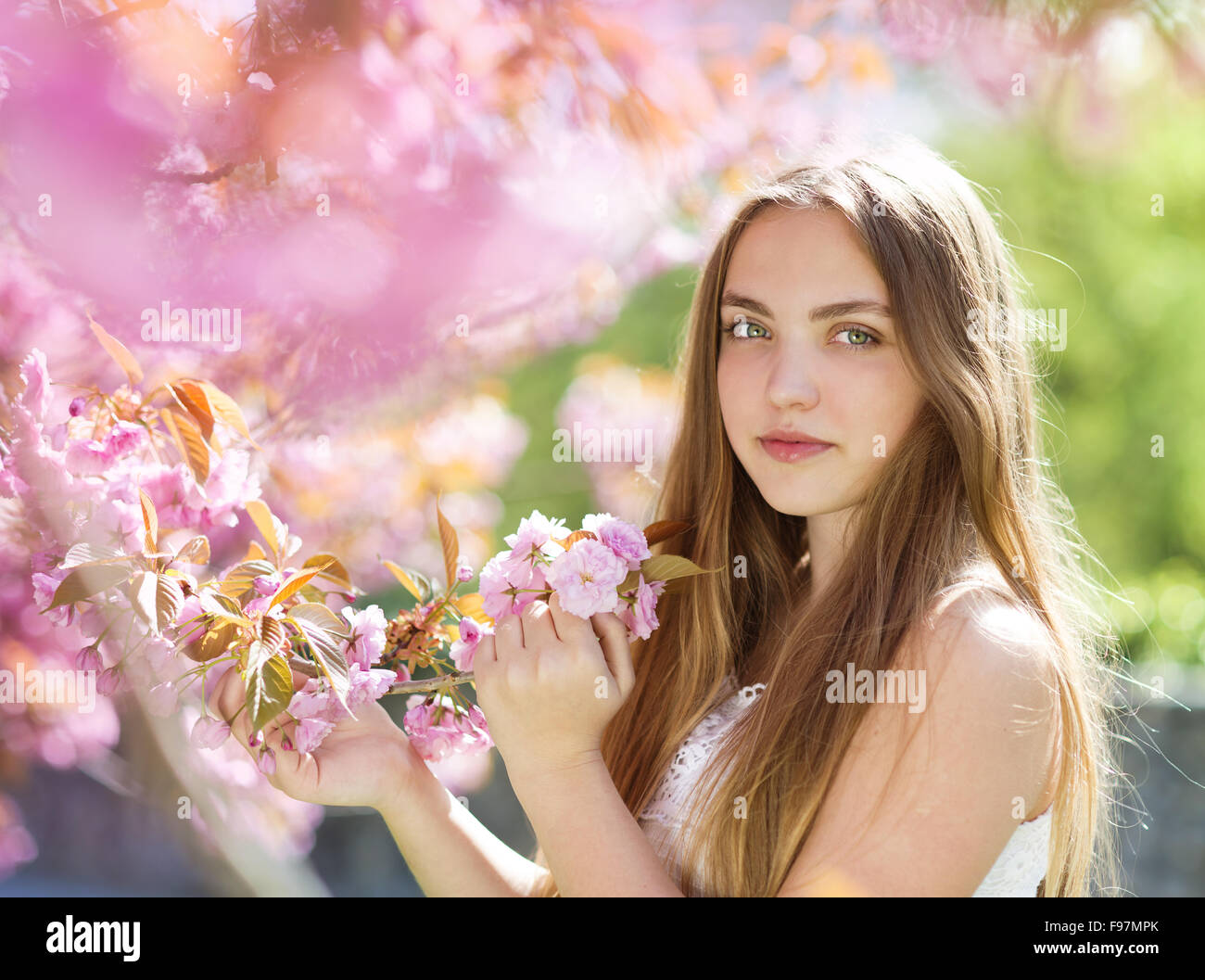 Beautiful girl in spring garden among the blooming trees with pink ...