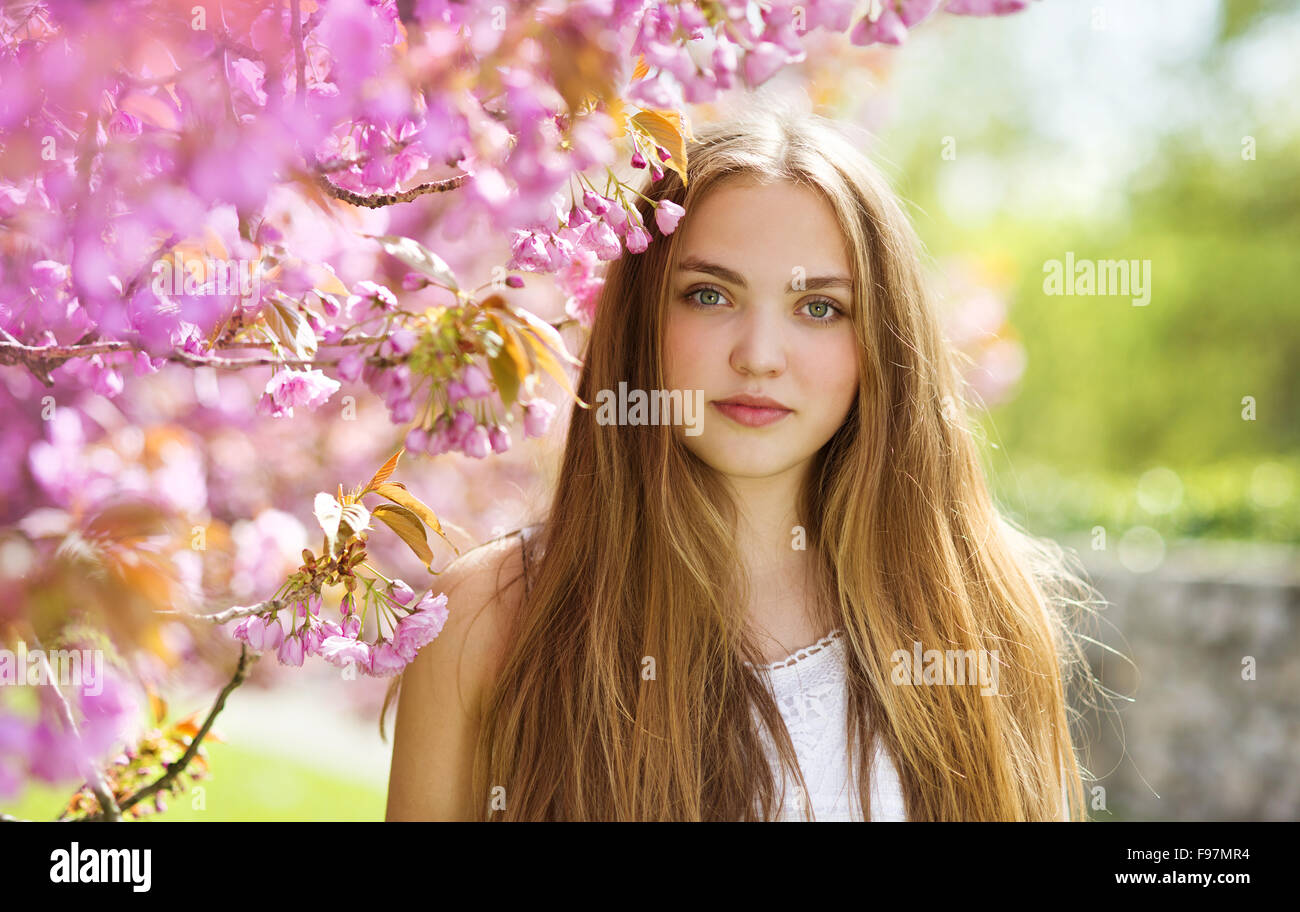Beautiful girl in spring garden among the blooming trees with pink ...