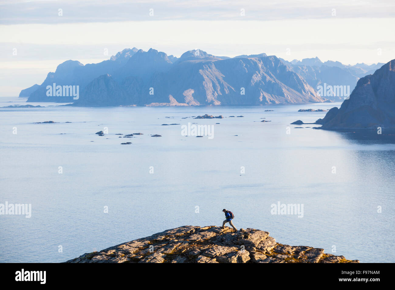 A hiker on Vaeroy Island, Lofoten Islands, Norway, with Mosken (right) and Moskenesoya Islands in the distance. Stock Photo