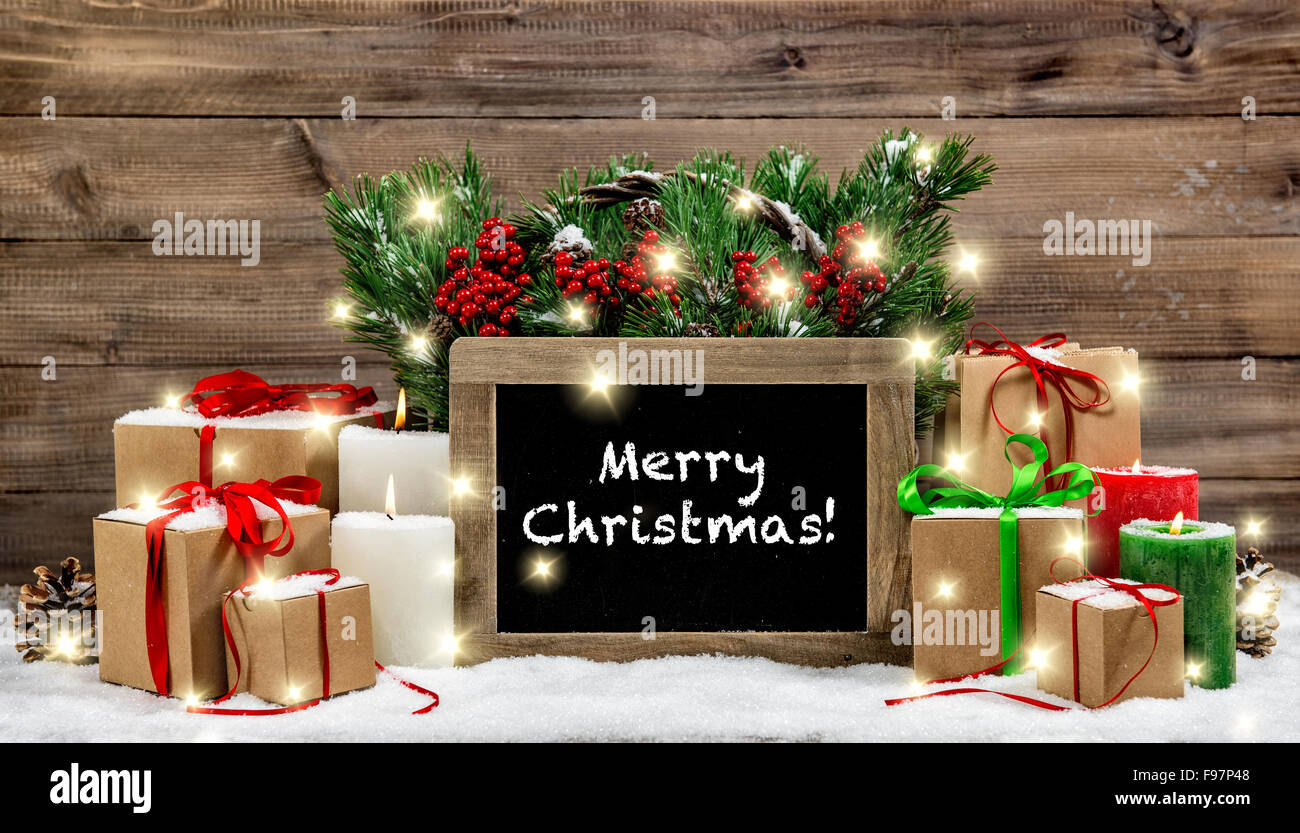 Christmas decoration burning candles and gift boxes. Chalkboard with sample text Merry Christmas! Vintage style toned photo with Stock Photo