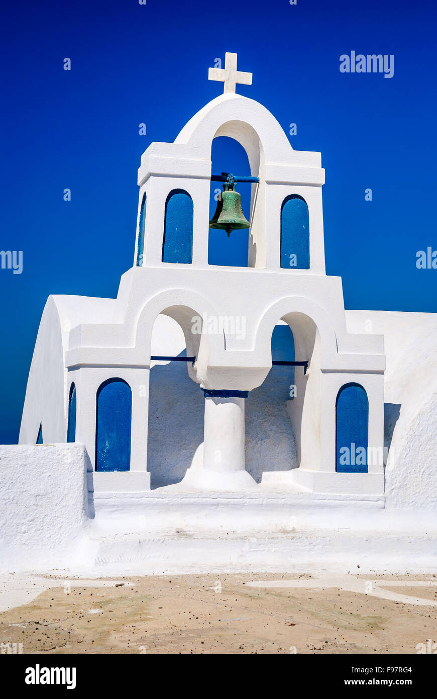 Santorini, Greek Islands. Architecture detail with white walls, church cross, bell and blue sky in Thira island of Aeagean Sea. Stock Photo