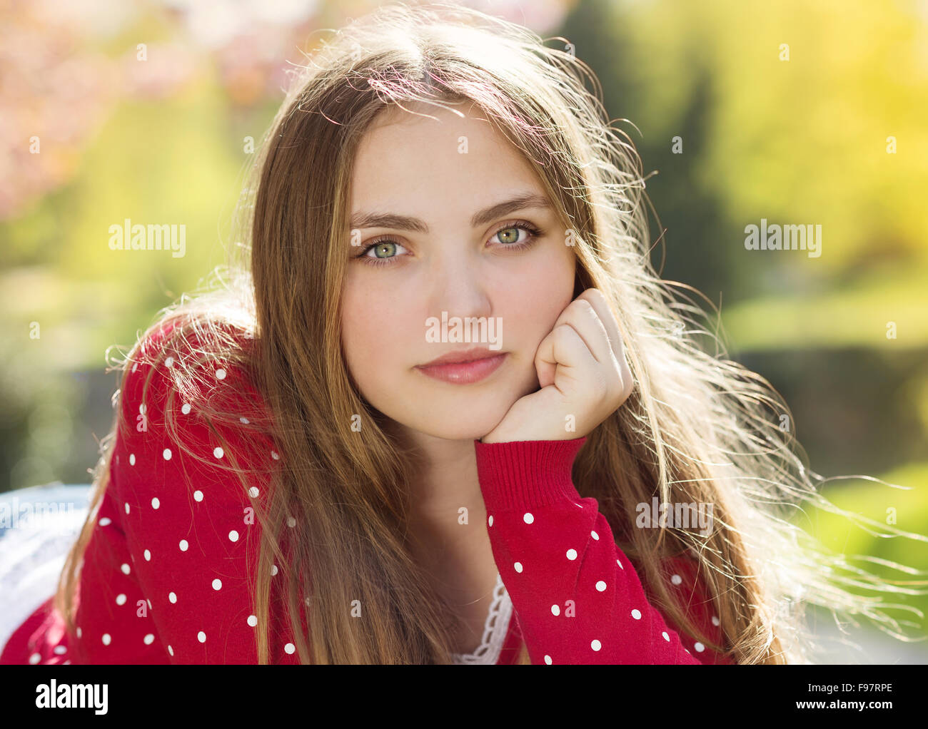 Portrait of beautiful girl in red cardigan in green prak Stock Photo