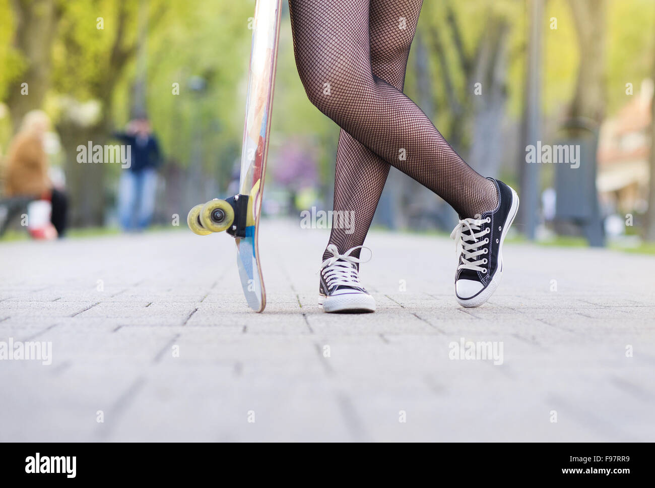 Close-up of legs of teenage girl holding skateboard Stock Photo