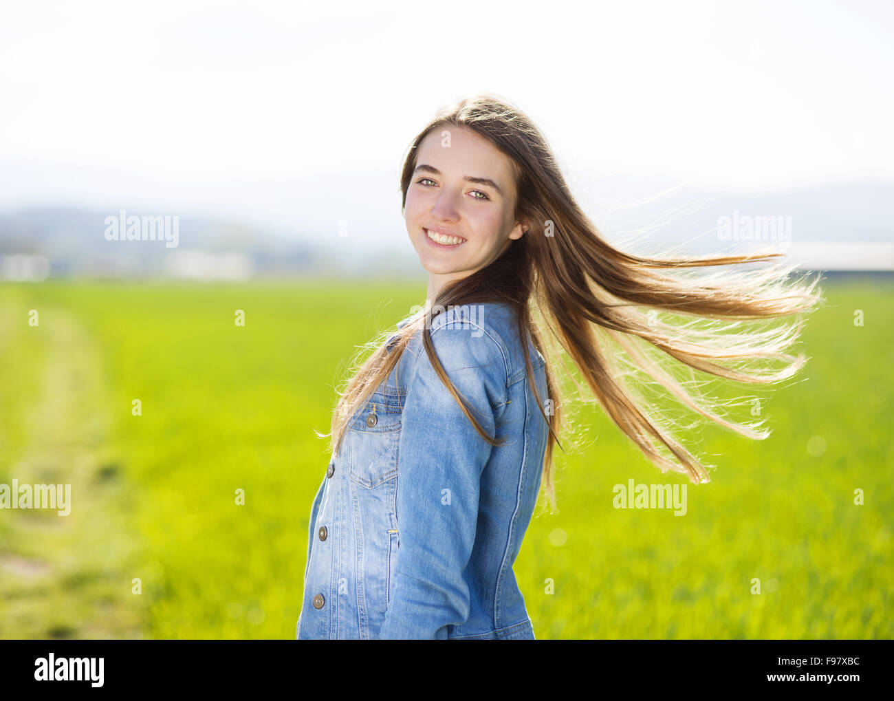 Happy Young Girl In Blue Jeans Jacket Enjoying Free Time In Green Field