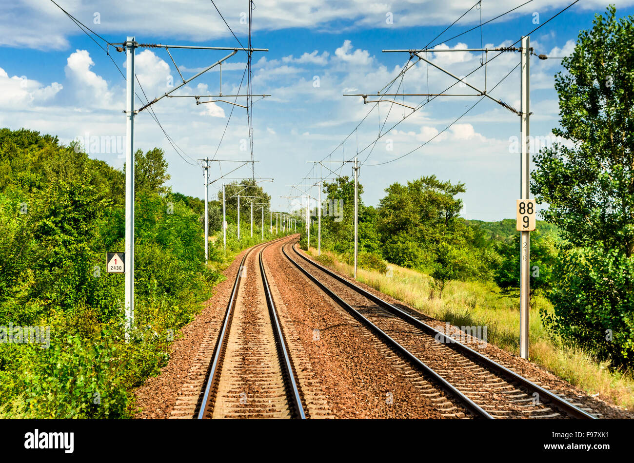 Amazing railway landscape in Romania with double electrified tracks in summer cloudy scenery. Stock Photo