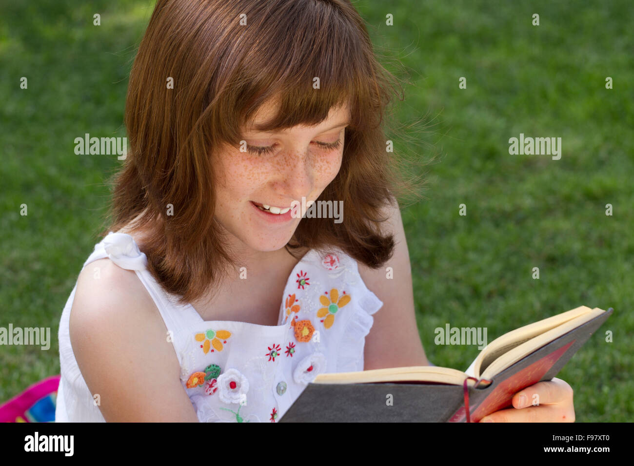 Young beautiful girl reading a book outdoor Stock Photo - Alamy