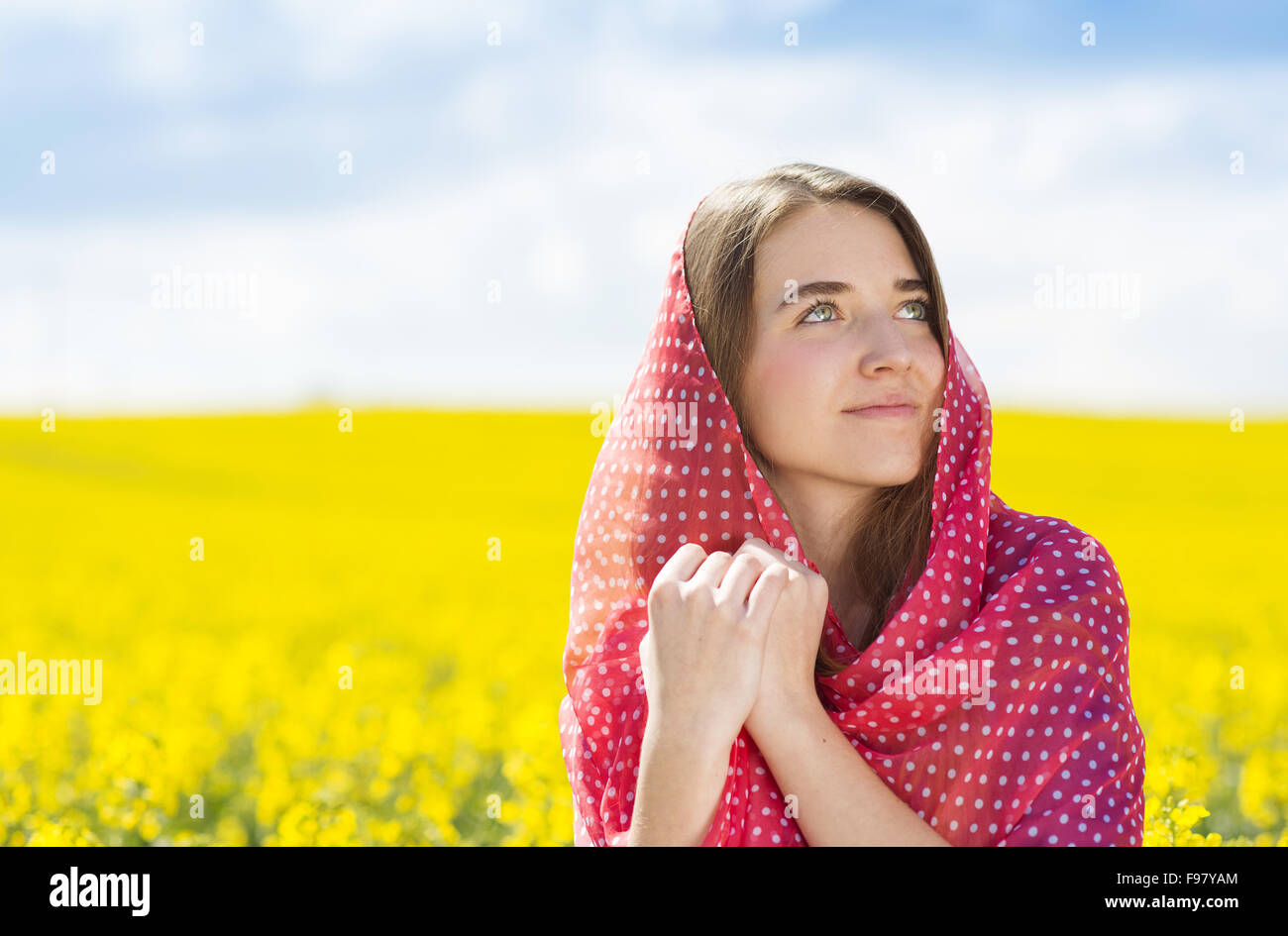 Happy young girl with red scarf enjoying free time in yellow colza field Stock Photo
