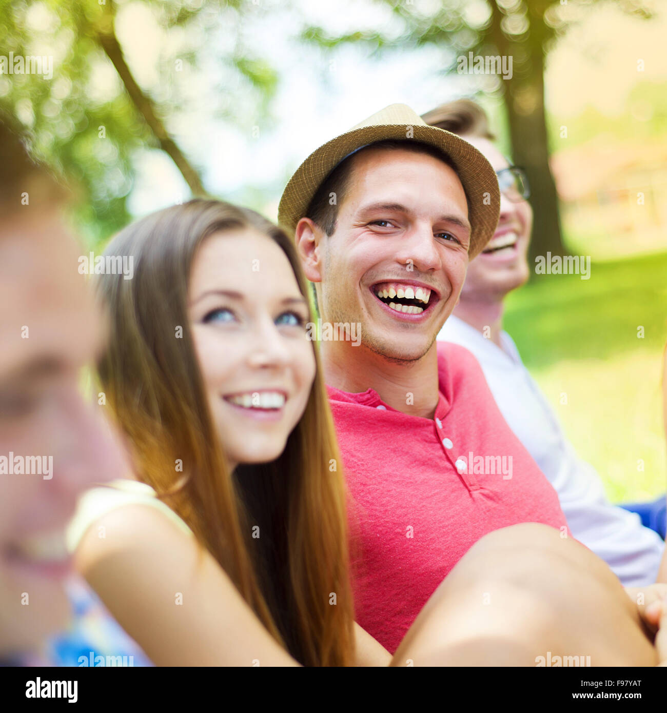 Group of young people having fun in park, sitting on the grass Stock Photo