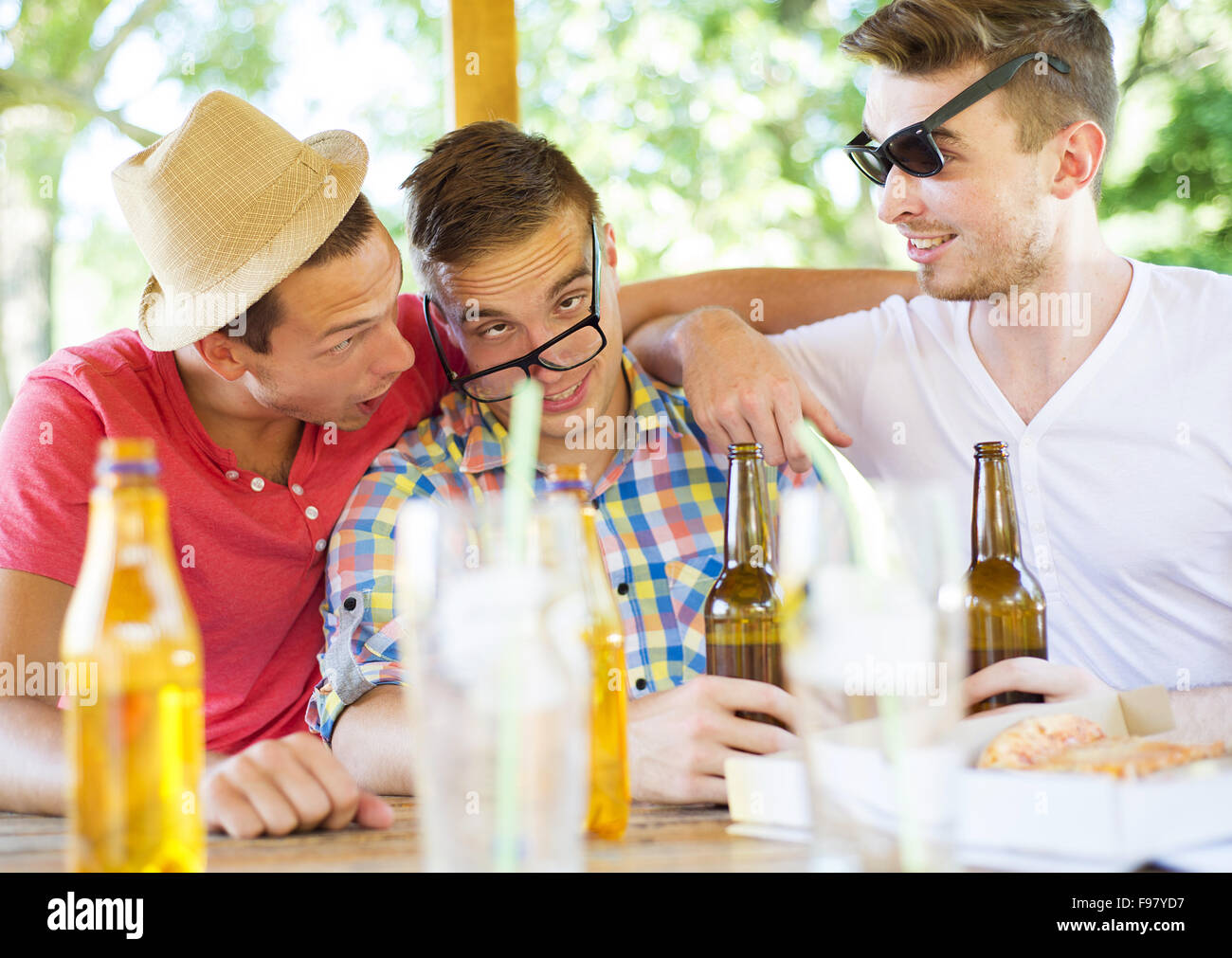 Three happy friends drinking beer, chatting and having fun in pub garden Stock Photo