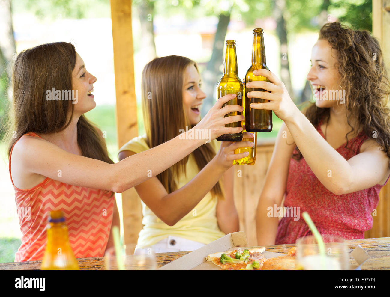 Three happy friends drinking beer, chatting and having fun in pub garden Stock Photo
