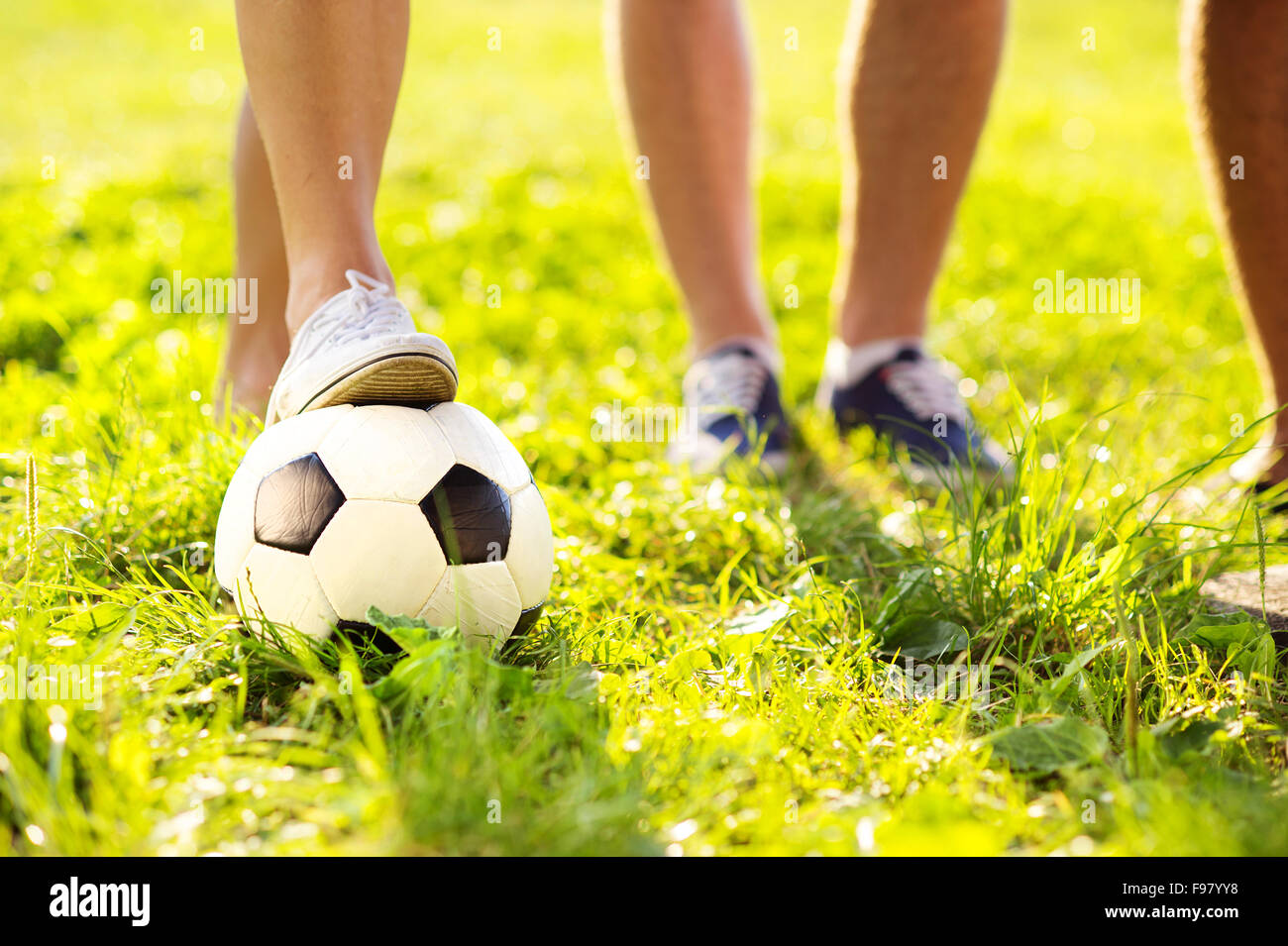 close up of feet and football ball on green grass lawn Stock Photo