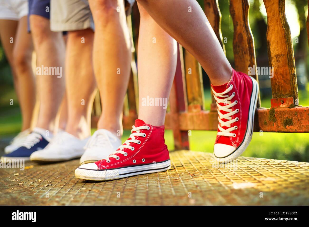 Legs and sneakers of teenage boys and girls standing on the sidewalk Stock Photo
