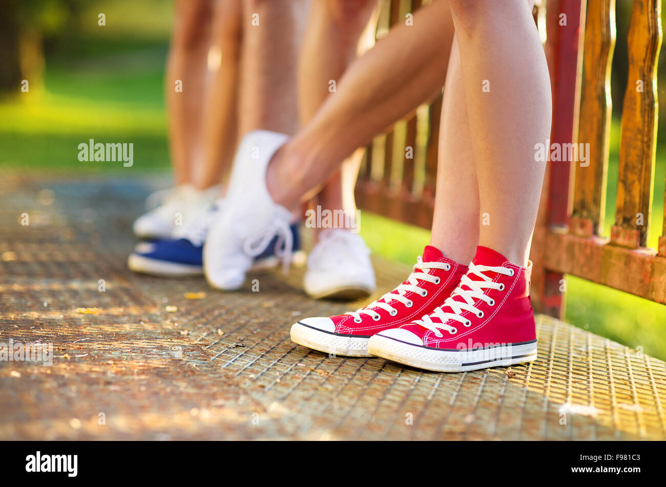 Legs and sneakers of teenage boys and girls standing on the sidewalk Stock Photo