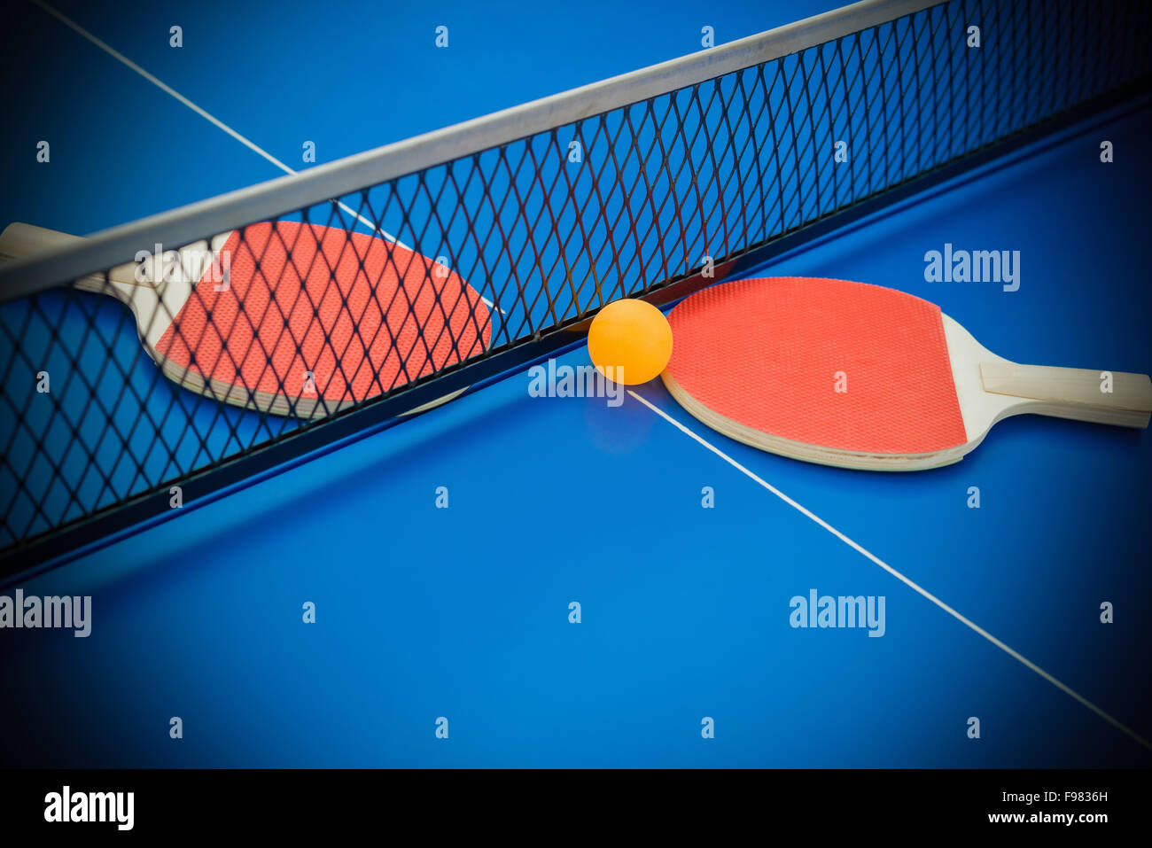 pingpong rackets and ball highlighted on a blue pingpong table Stock Photo