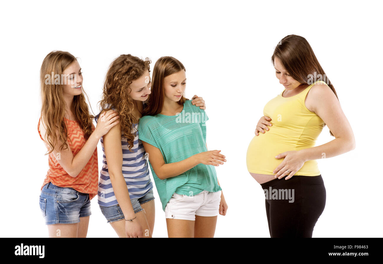 Female friends looking at tummy of a pregnant woman, isolated on white background Stock Photo