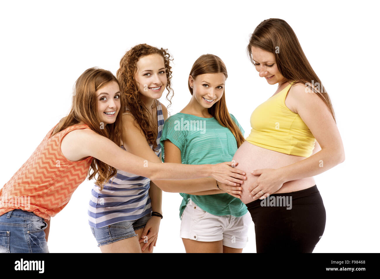 Female friends touching tummy of a pregnant woman, isolated on white background Stock Photo