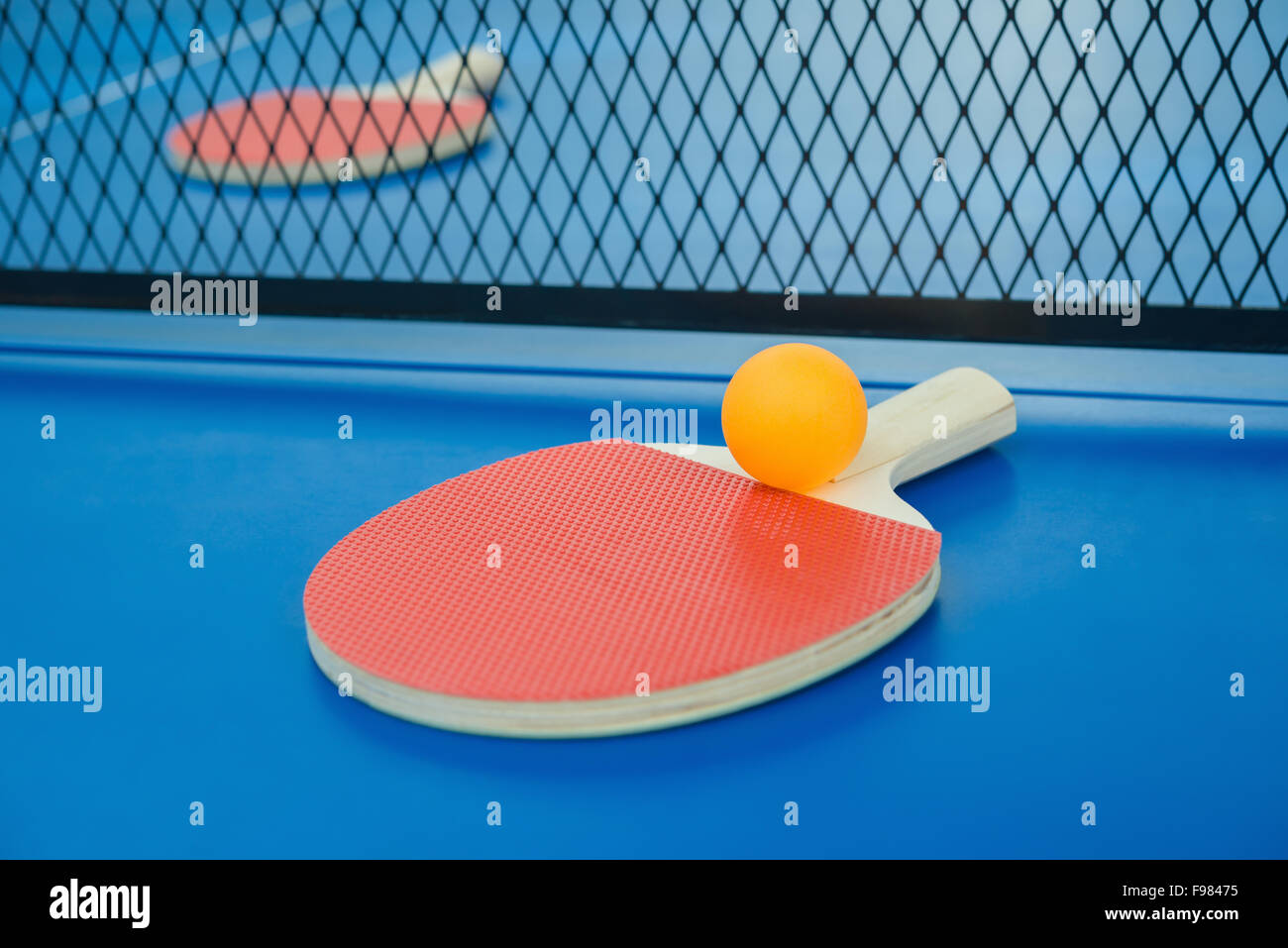 pingpong rackets and ball and net on a blue pingpong table Stock Photo