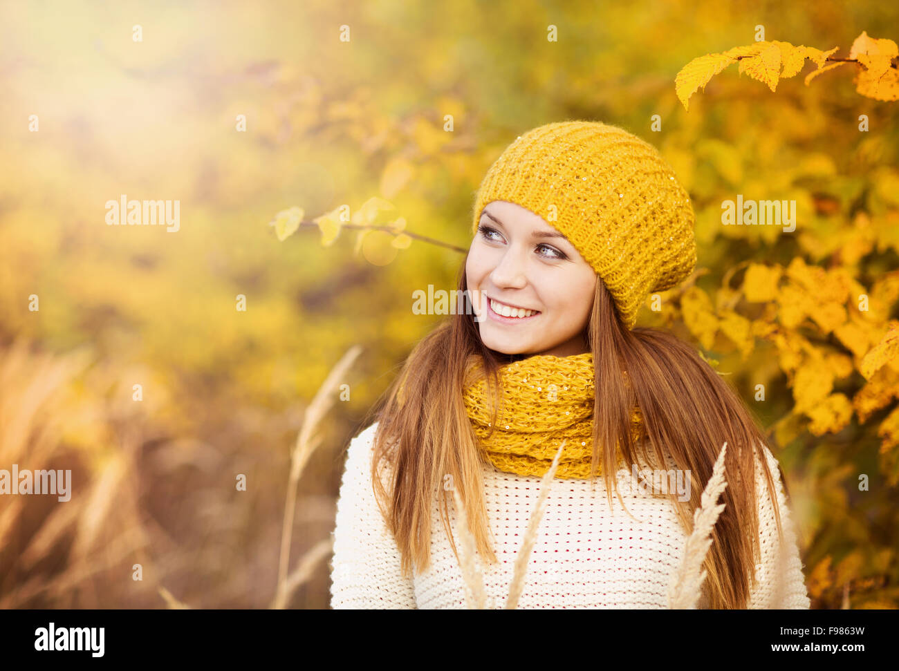 Portrait of beautiful girl with scarf and hat in yellow autumn nature ...