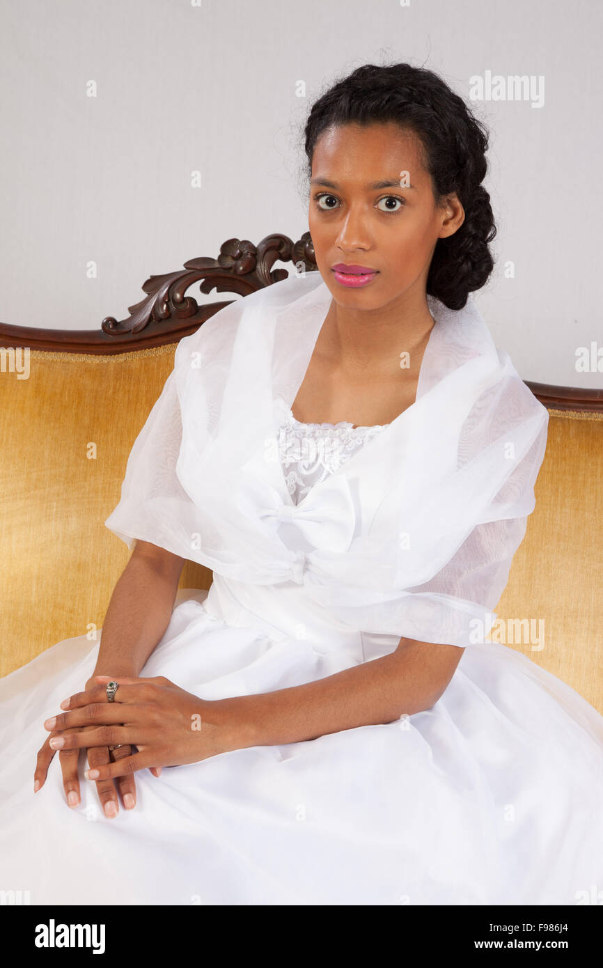 Pretty black woman in a white wedding type of dress, looking thoughtful Stock Photo