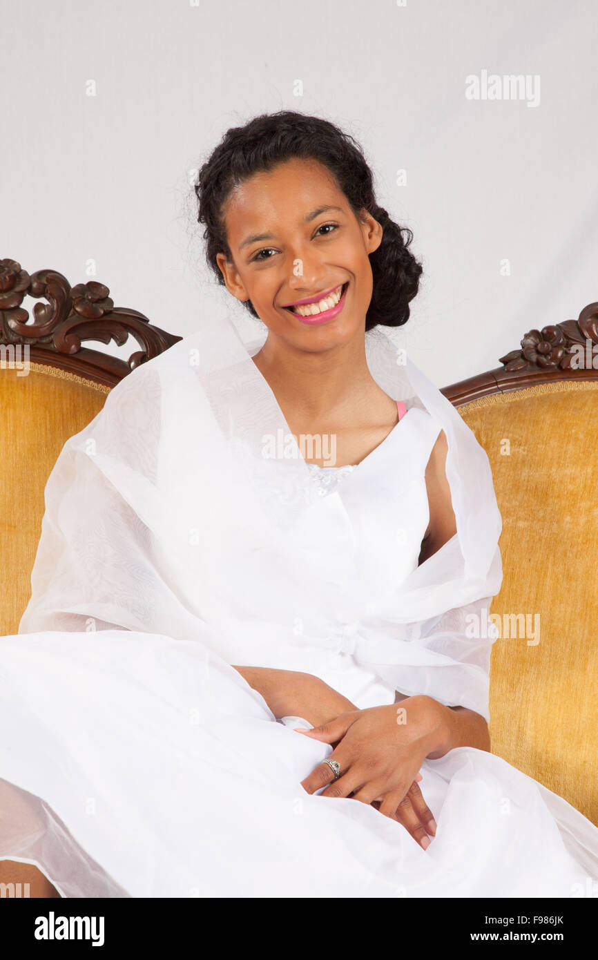 Pretty black woman in a white wedding type of dress, looking happy Stock Photo