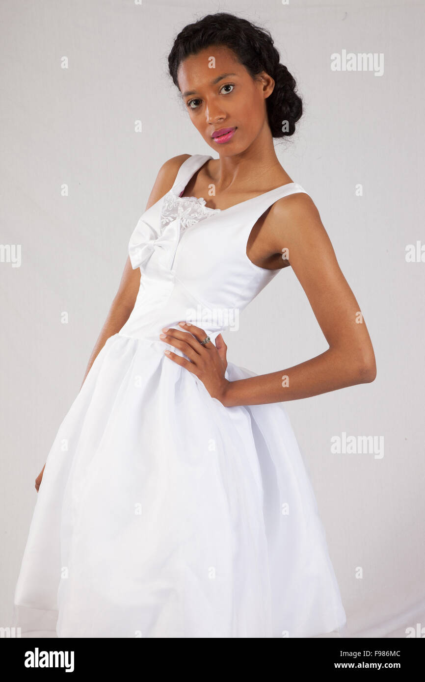 Pretty black woman in a white wedding type of dress, looking thoughtful Stock Photo
