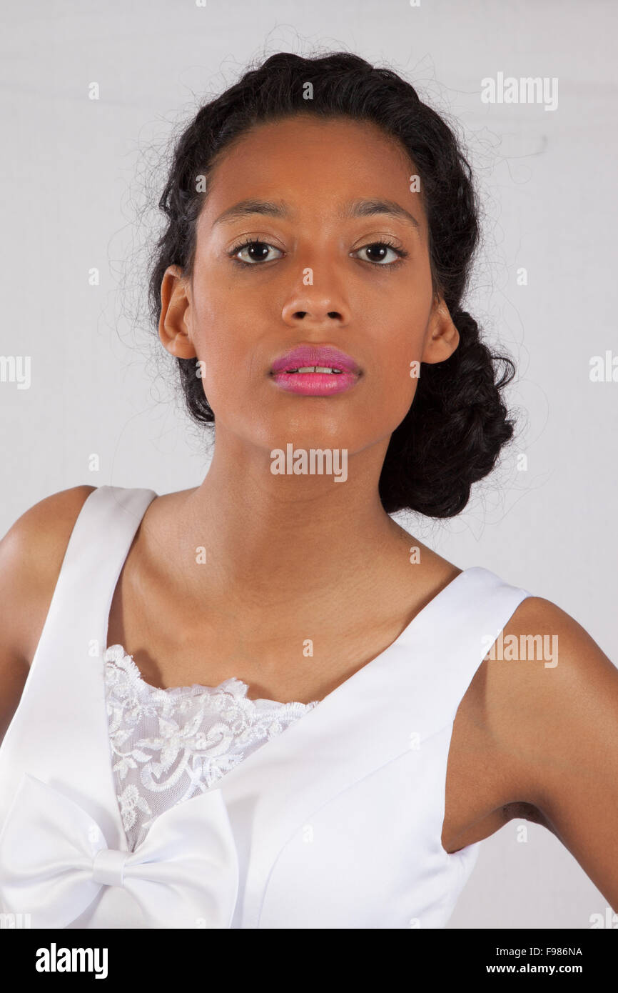 Pretty black woman in a white wedding type of dress, looking thoughtful Stock Photo