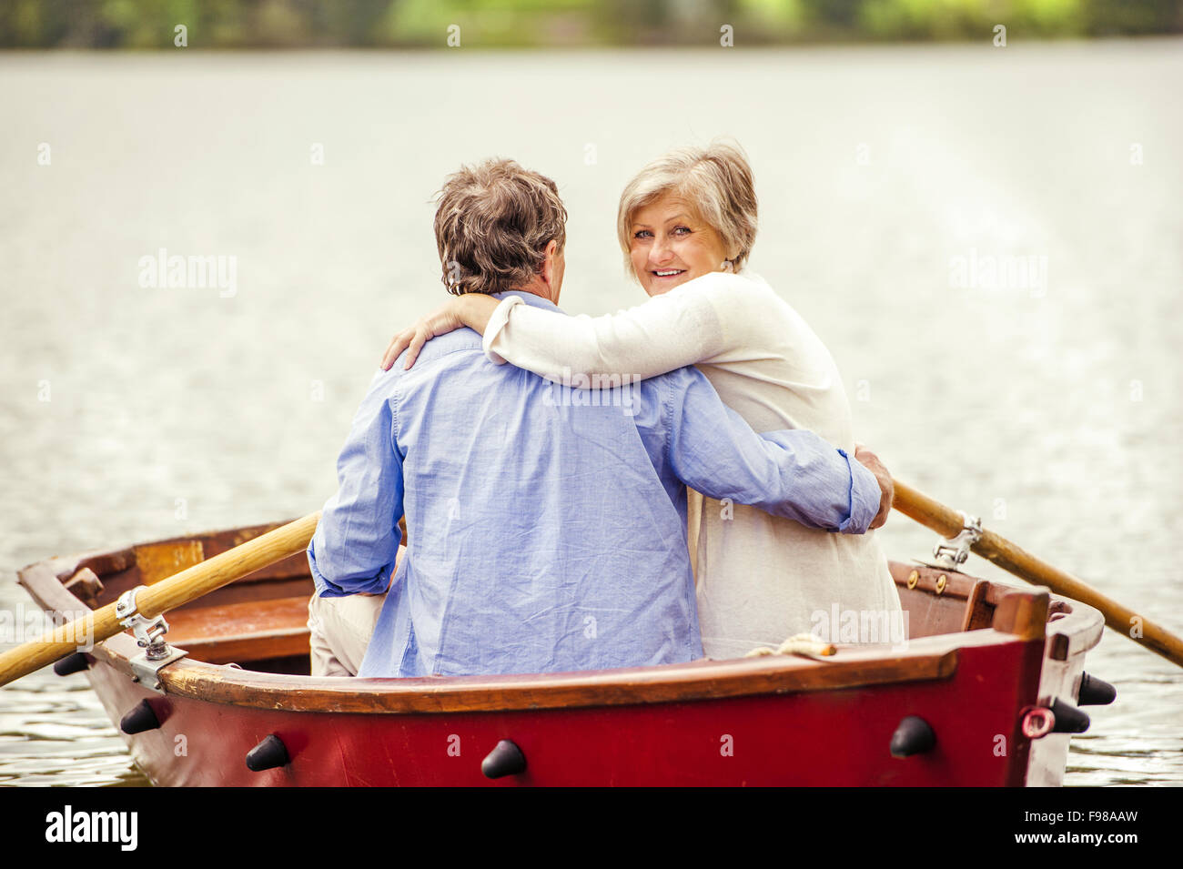 Senior couple paddling on boat on mountain tarn Stock Photo