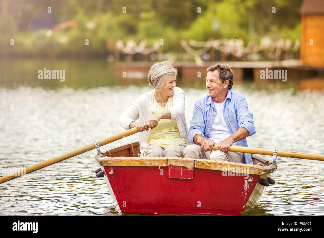 Senior couple paddling on boat on mountain tarn Stock Photo