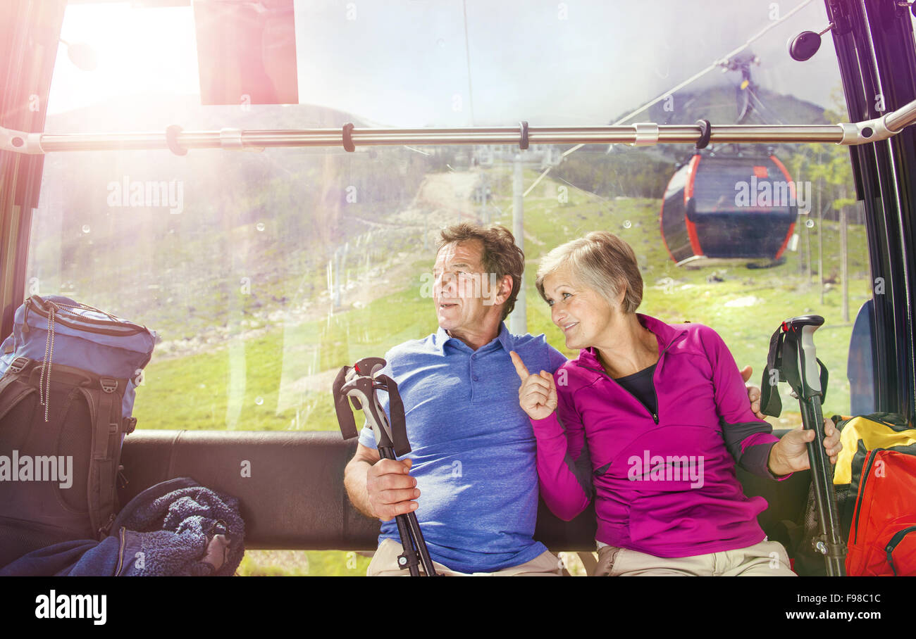 Senior hikers couple going up the mountain by cableway Stock Photo