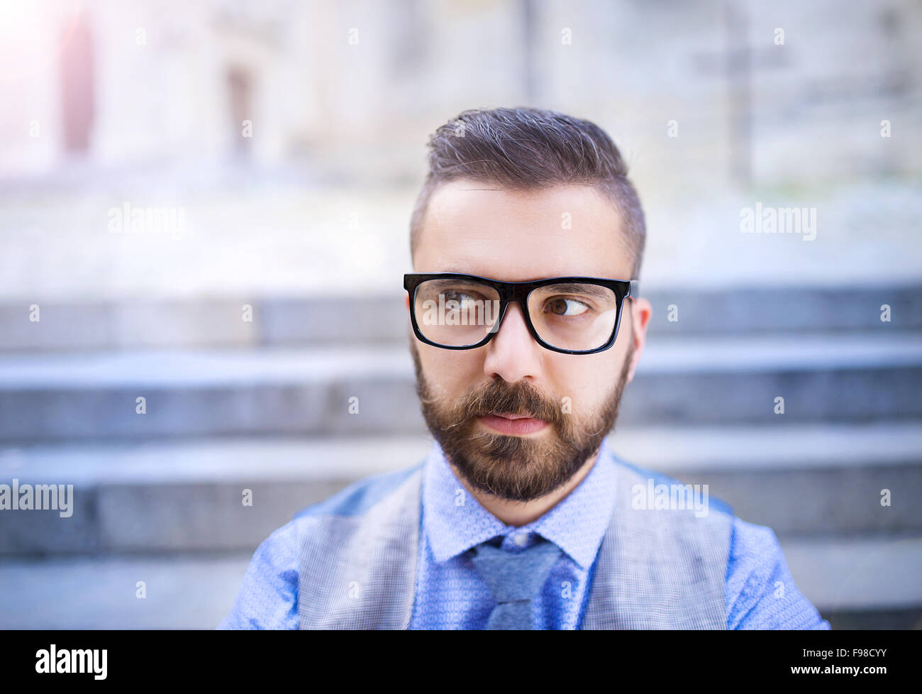 Handsome hipster modern businessman with beard and glasses in town Stock Photo