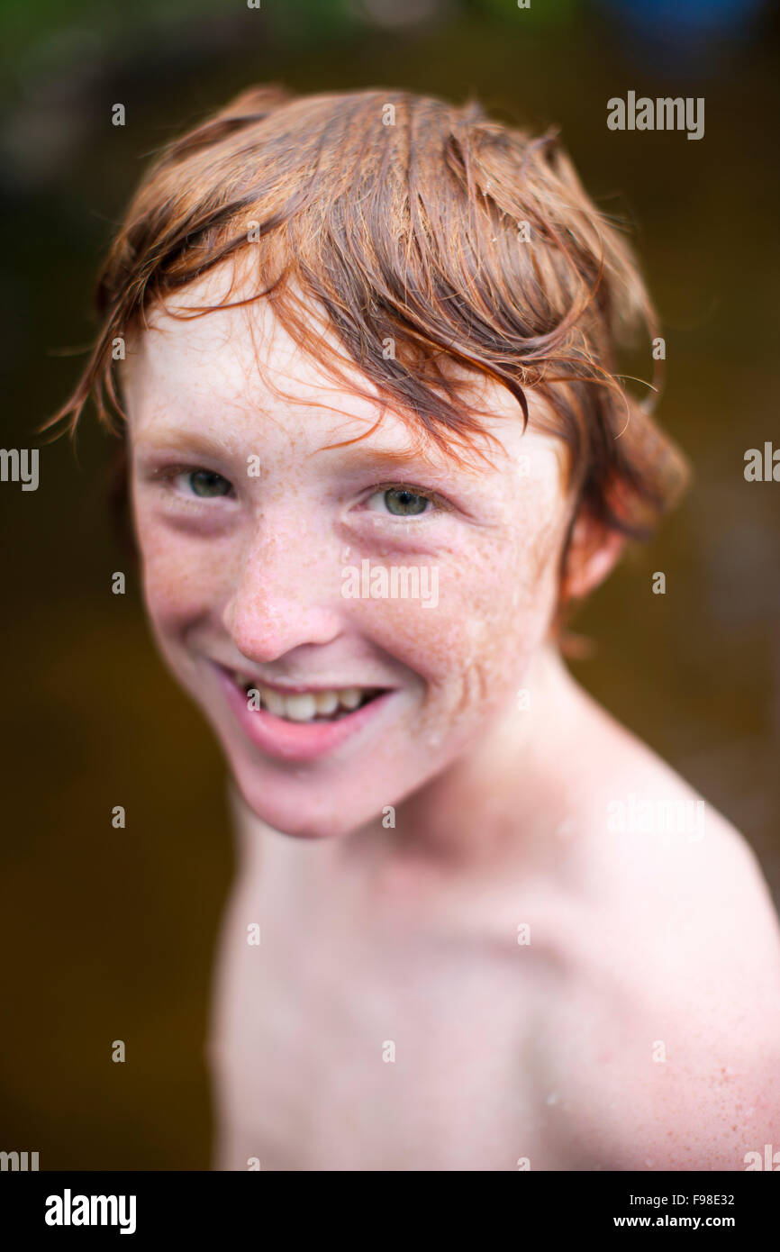 A young red head boy with wet hair smiles. Stock Photo