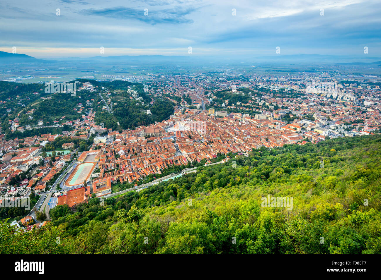 Aerial view of Brasov old town nestled in a valley with snow-capped mountains, visible from Tampa Mountain.