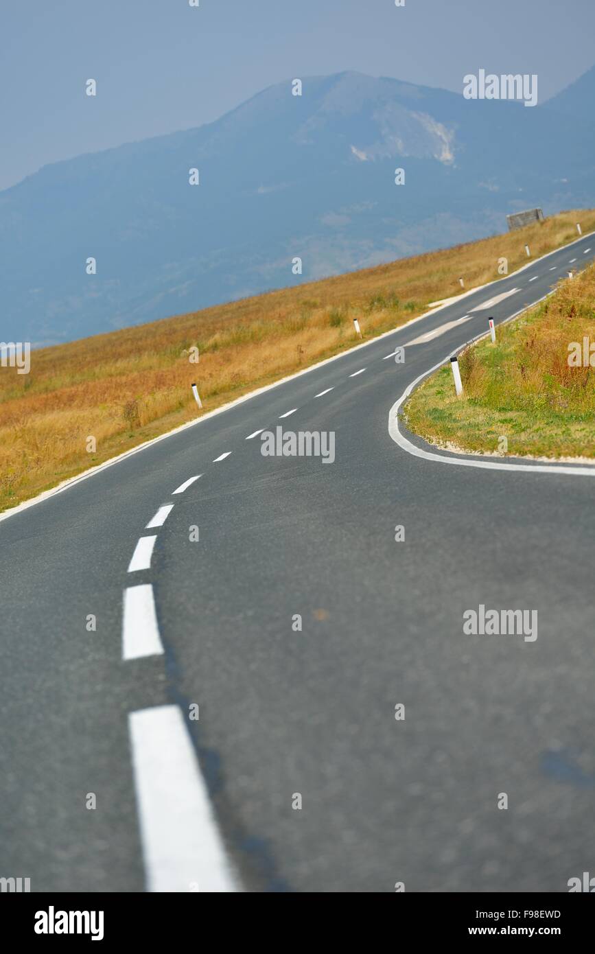 asphalt road through the green field and clouds on blue sky in summer ...