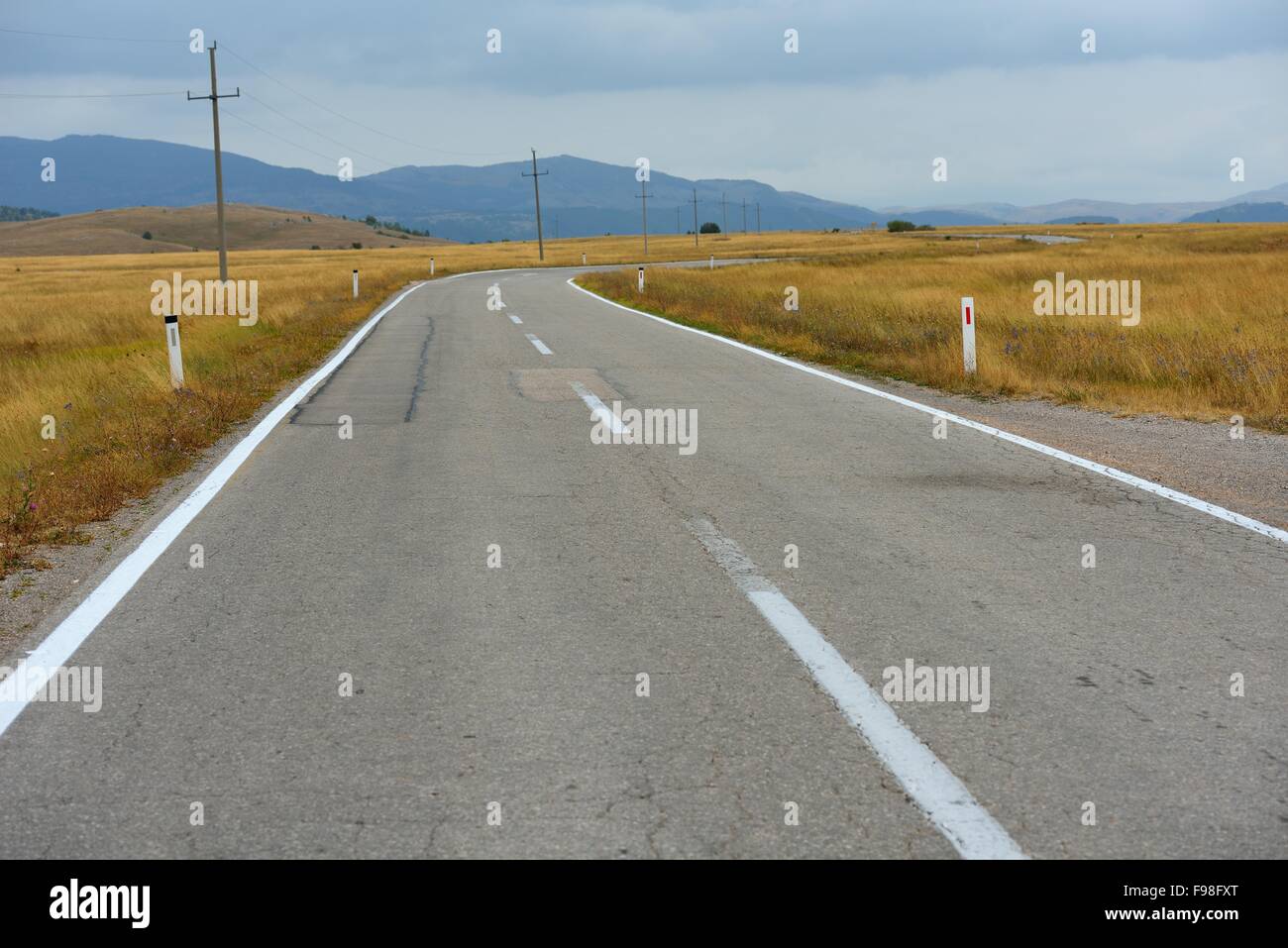 asphalt road through the green field and clouds on blue sky in summer ...