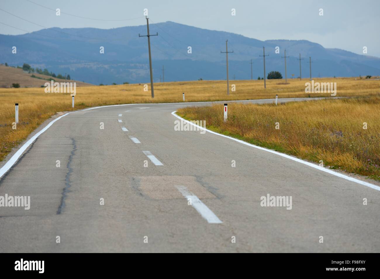 asphalt road through the green field and clouds on blue sky in summer ...