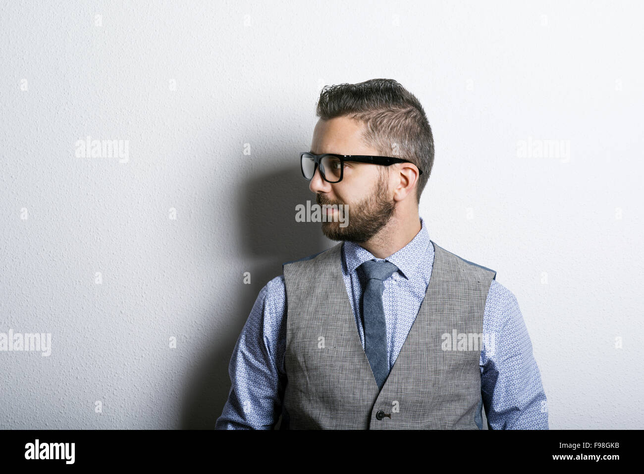 Studio shot of modern hipster businessman leaning against wall Stock Photo