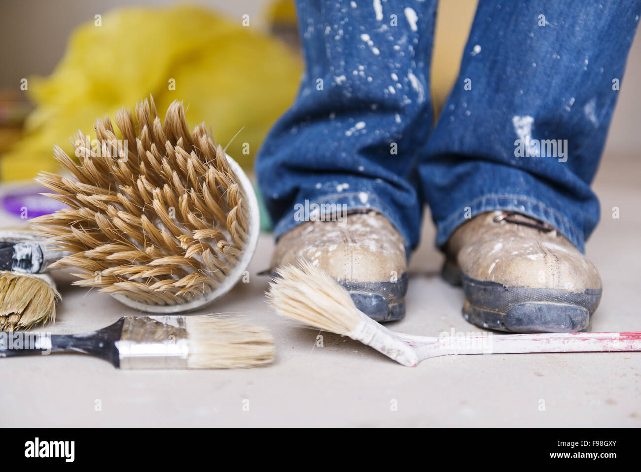 Preparing to paint the wall. Detail of man's feet painting the walls of new home. Stock Photo