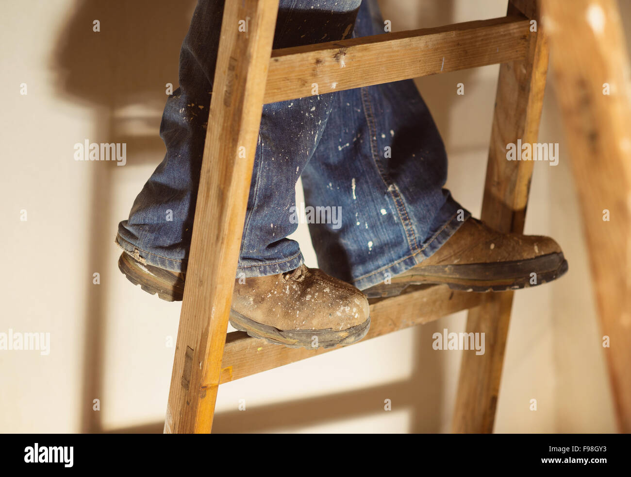 Preparing to paint the wall. Detail of man's feet standing on the ladder Stock Photo