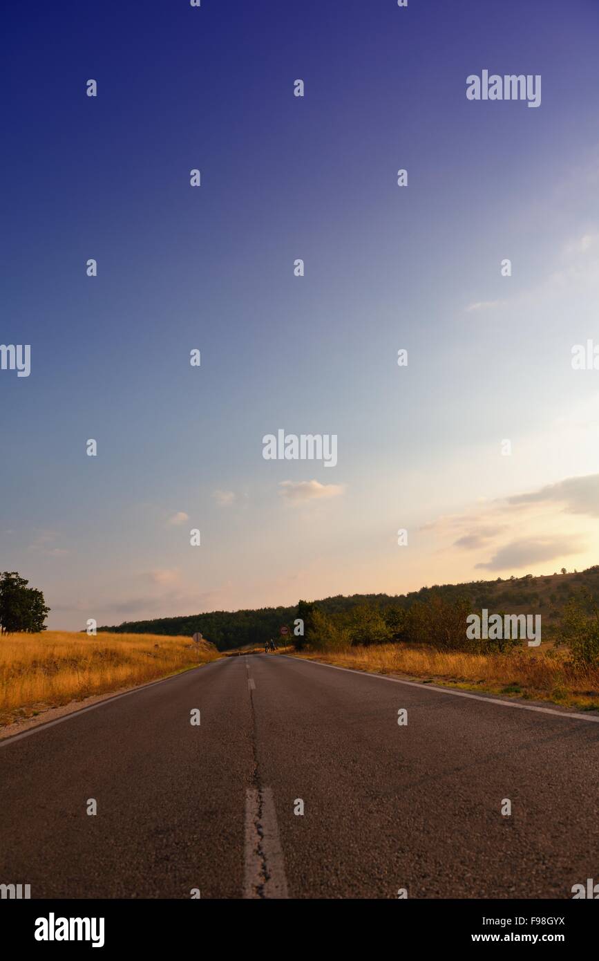 asphalt road through the green field and clouds on blue sky in summer ...