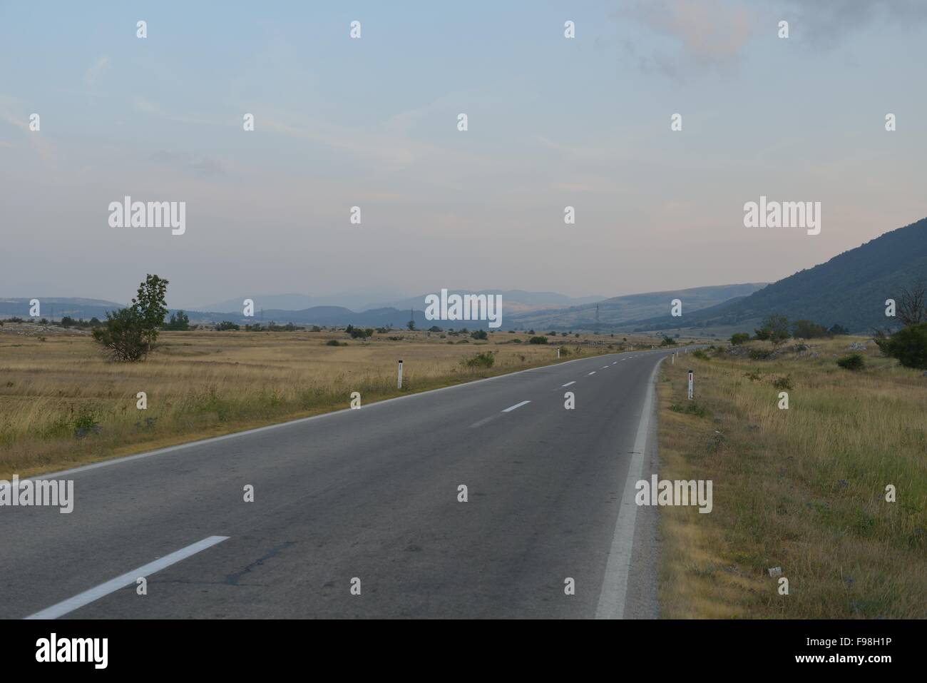 asphalt road through the green field and clouds on blue sky in summer ...