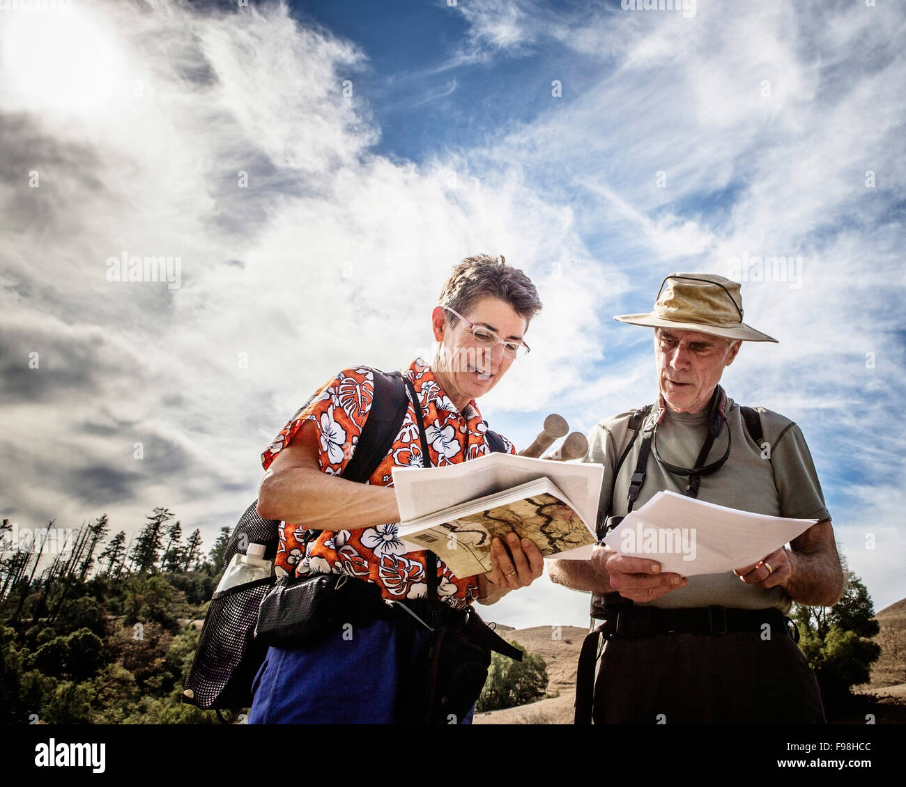 A male and female hiker stop to consult a book and map. Stock Photo