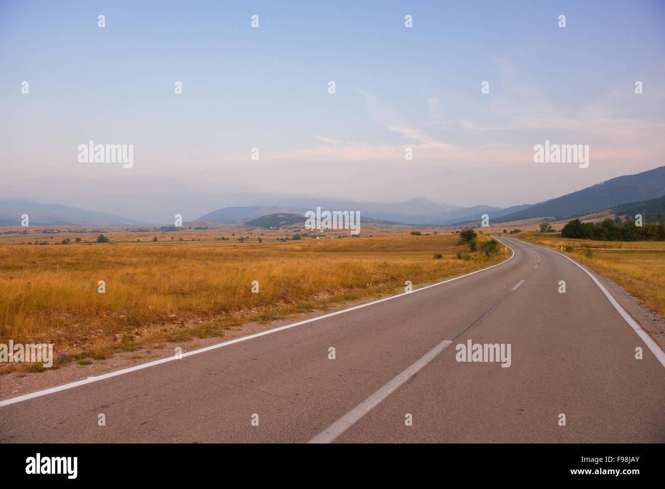 asphalt road through the green field and clouds on blue sky in summer ...