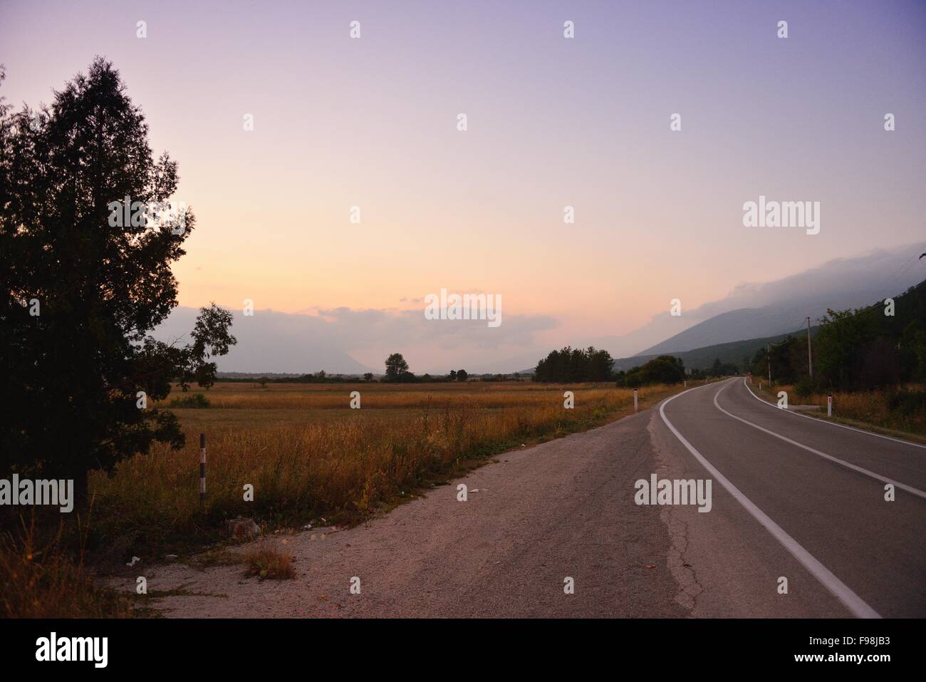 asphalt road through the green field and clouds on blue sky in summer ...