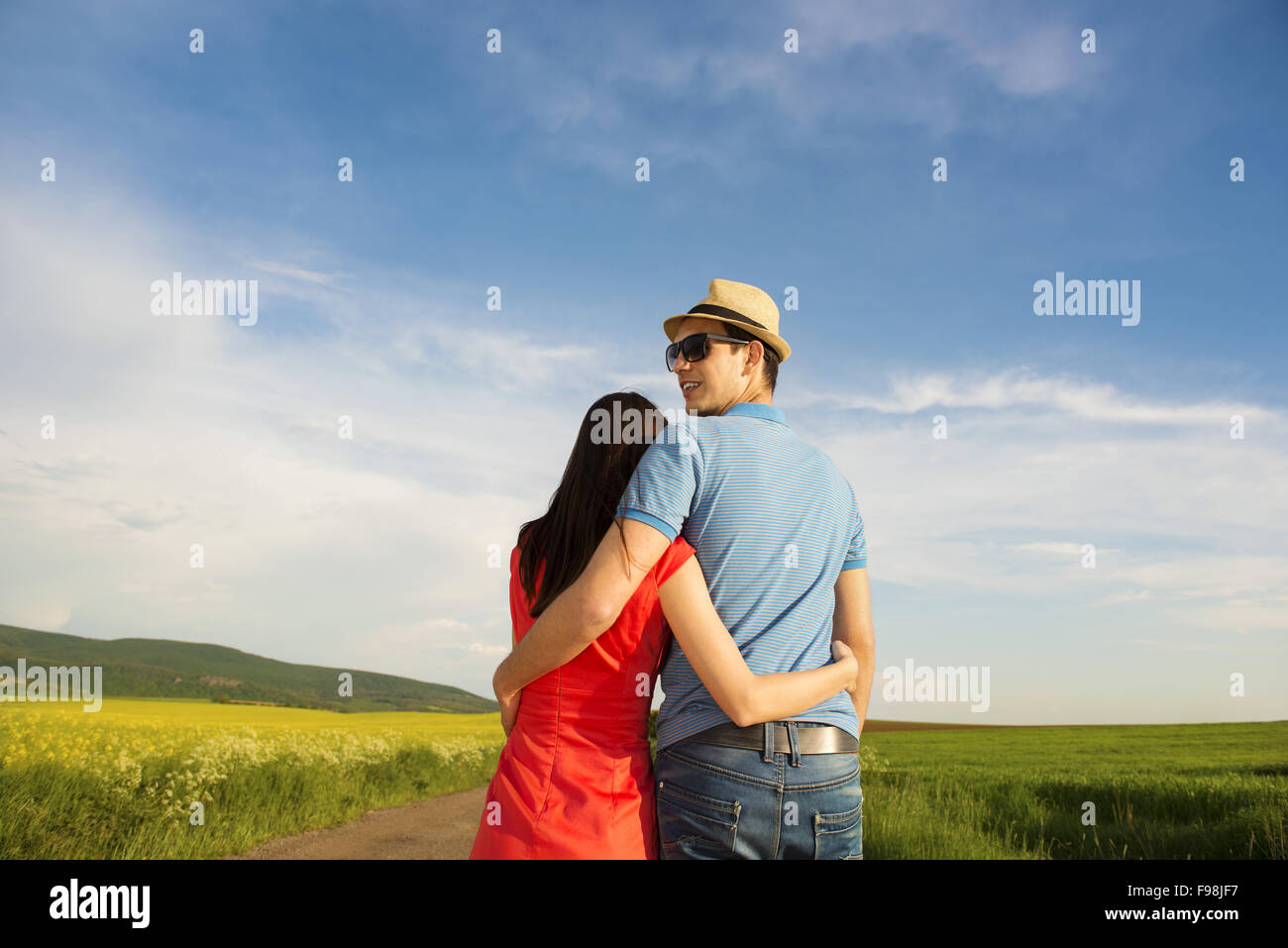 Happy Young Couple In Love Hugging On Countryside Road Next To The